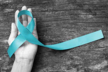 Turquoise or Robin egg blue ribbon on human hand old aged background raising awareness on Bone tumor, Addiction recovery  clipart