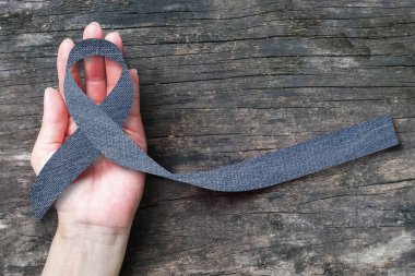 Blue jeans denim ribbon (isolated with clipping path) on helping hand support and aged wood for genetic disorder awareness and children's rare disease illness  clipart