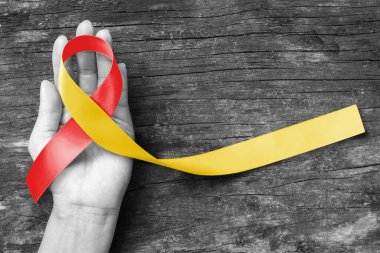 Dünya hepatit günü ve HIV / HCV ortak enfeksiyon farkındalığı kişinin el desteği ve eski ahşap üzerinde kırmızı sarı kurdele (kırpma yolu ile izole edilmiş) ile