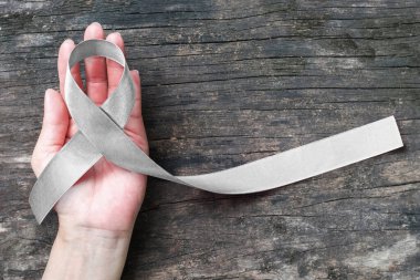 Parkinson hastalığı farkındalığı ve beyin kanseri tümörü hastalığı için el desteğinde gümüş renkli kurdele ve yaşlandırılmış ahşap (kırpma yolu ile izole)