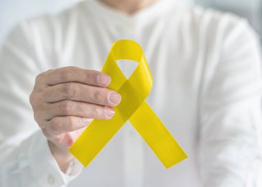 İntihar önleme için sarı kurdele sembolik renk ve Sarkoma Kemiği kanseri kişinin elinde farkındalığı