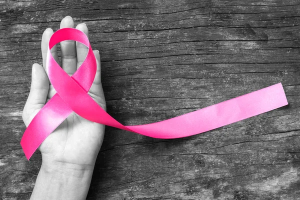 为提高对乳腺癌的认识和开展妇女健康运动 在妇女的手上绑上粉红的芙蓉丝带 用剪路隔开 — 图库照片