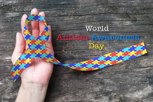 World Autism awareness day with multi-color puzzle ribbon on person\'s hand