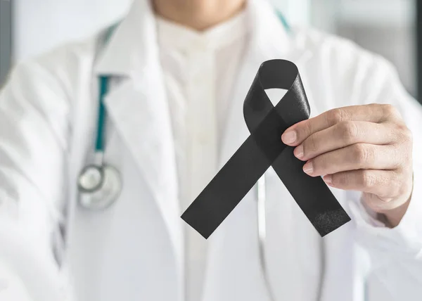 Black ribbon awareness in doctor's hand for Melanoma and skin cancer, Narcolepsy, Primary Biliary Cirrhosis (Cholangitis), Sleep Apnea Disorder