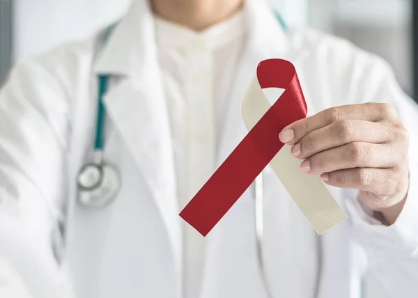 Doktorun elinde Burgundy fildişi kurdele farkındalığı, kafa ve boyun kanseri için sembolik yay rengi, ağız tümörü kanseri, boğaz, gırtlak ve gırtlak kanseri
