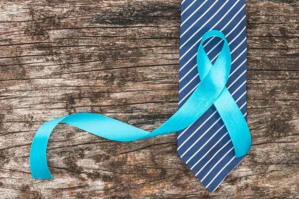 Prostate cancer awareness concept with light blue ribbon on necktie and old aged wood for men's health care campaign in November and September month