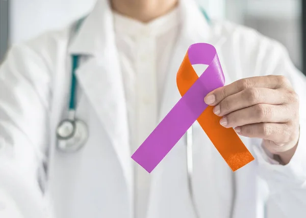 Sedef hastalığı ve egzama dermatit hastalığı. Doktorun el desteğinde orkide mor turuncu kurdele renginde bir kampanya konsepti. 