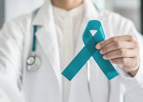 Doktorun elindeki Teal farkındalık kurdelesi, yumurtalık kanseri, PCOS ve PTSD hastası hastaları desteklemek için sembolik yay rengi
