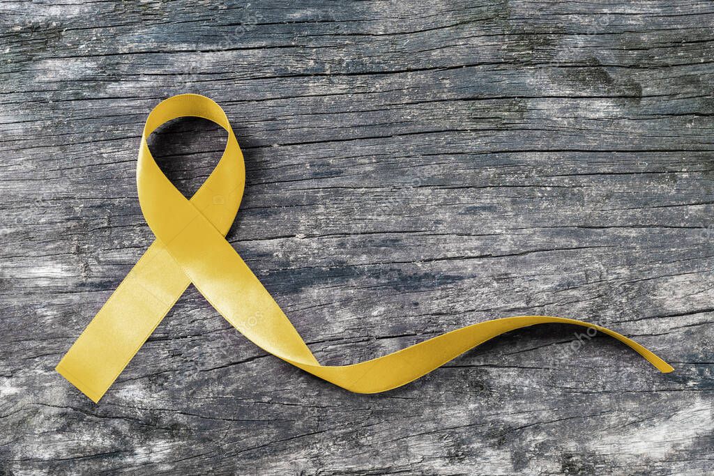 Yellow ribbon symbolic color for Sarcoma Bone cancer awareness and suicide prevention on aged wood (isolated with clipping path)