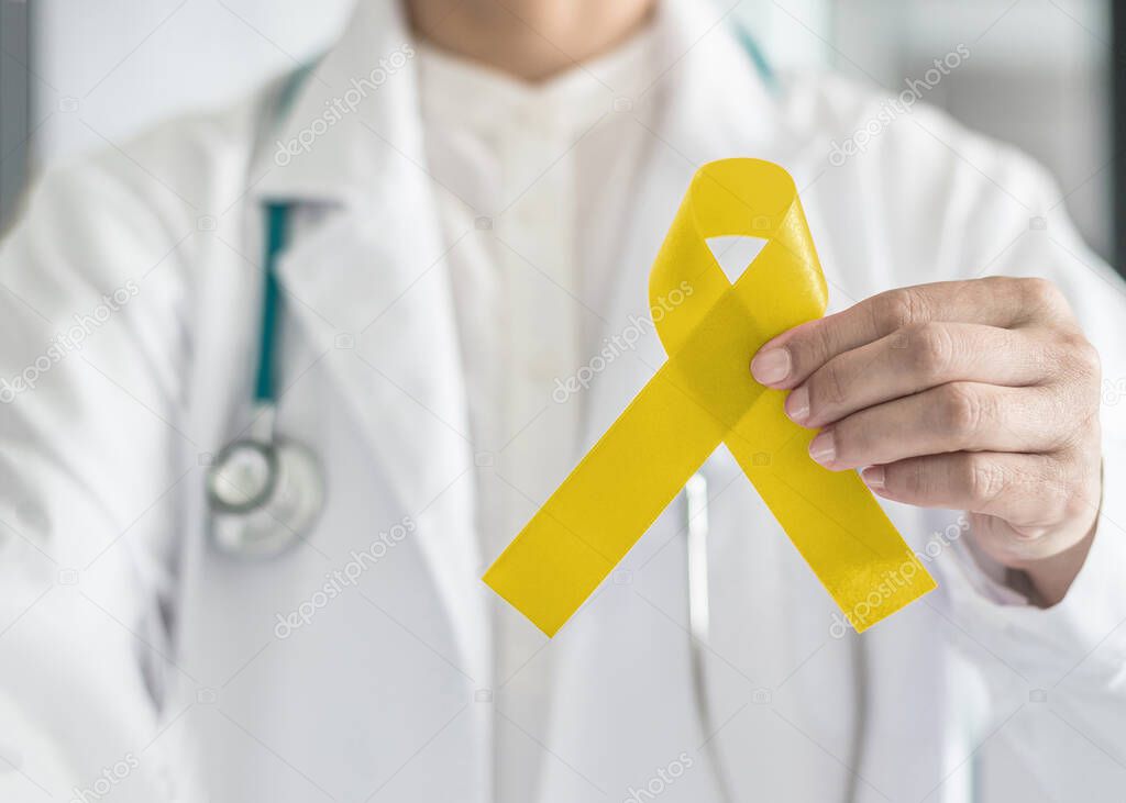 Yellow ribbon symbolic color for Sarcoma Bone cancer awareness and suicide prevention in doctor's hand
