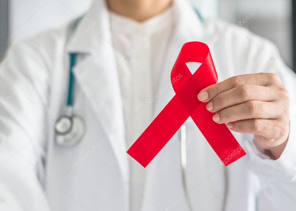 Aids red ribbon in doctor hand for World aids dayand HIV virus awareness concept 