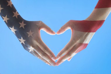 Amerikan bayrak deseni insanların ellerinde. Mavi gökyüzünde kalp şeklinde.