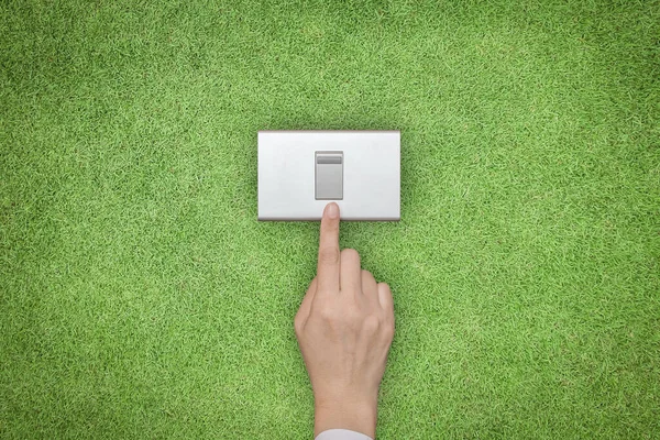 Energy saving and ecological friendly concept with hand turning off switch on green grass lawn
