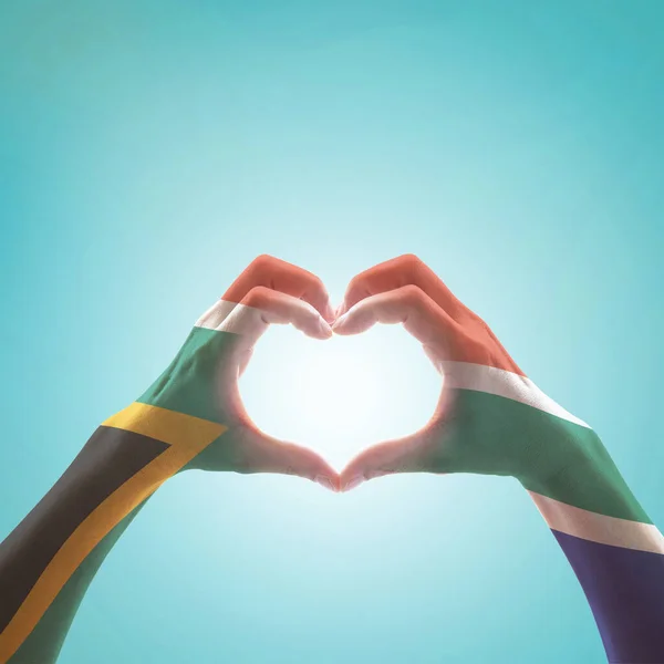 South Africa flag on woman hands in heart shape isolated on mint background for national unity, union, love and reconciliation concep