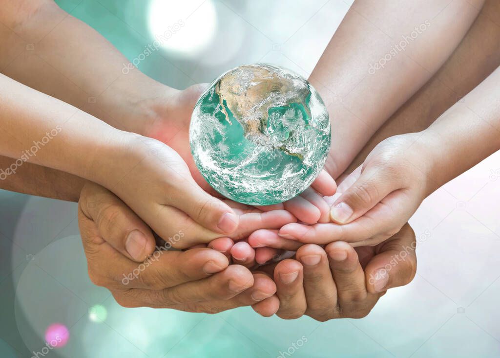 Green globe in family volunteer hands for earth day and CSR with people concept. Elements of this image furnished by NASA.