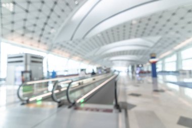 Havaalanı, yolcu terminalinde yürüyen merdivende yürüyen bavullu yolcu ve hosteslerle dolu arka planda bulanıklık yarattı. 