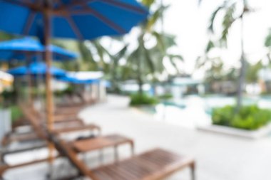 Otel havuzunun yaz bulanık arka planında havuz kenarında mavi serin gökyüzü ve tropikal palmiye ağacı olan bir parti var.