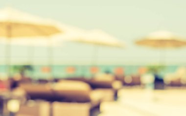Yaz bulanık arka plan havuz partisi tropikal tatil havuzu yüzme tatil tatil yeri ve bulanık mavi okyanus veya parlak güneşli gökyüzü altında deniz manzaralı plaj şemsiyesi.