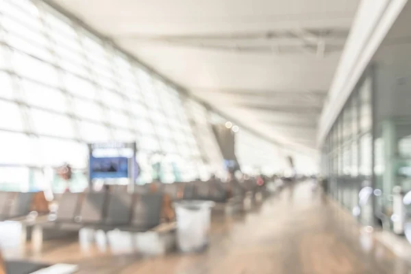 Airport blur background for air transportation travel concept with blurry bench seats for traveller or tourist on corridor in waiting area of airport departure flight or bus terminal building interior