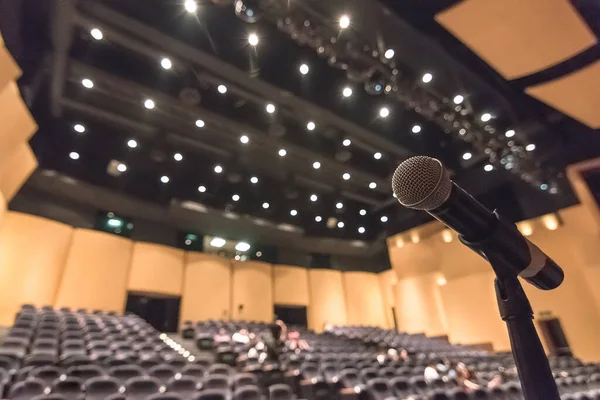 Speaker\'s microphone blurred in blurry auditorium music concert hall background or seminar meeting room in educational business conference event