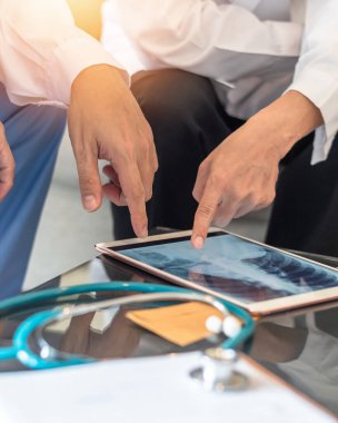 COVID-19 ve doktor ekip çalışması akciğer enfeksiyonu teşhisini dijital tablette göğüs röntgenine koydu ve acil servis tıbbi ekibi hastanede hasta bakımı ve tedavisi üzerinde tartıştı.