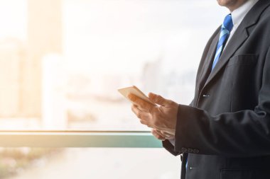 İş adamı internet kablosuz iletişimini cep telefonu dokunmatik ekranı ve dijital çevrimiçi uygulama teknolojisini kullanarak çalışıyor. 