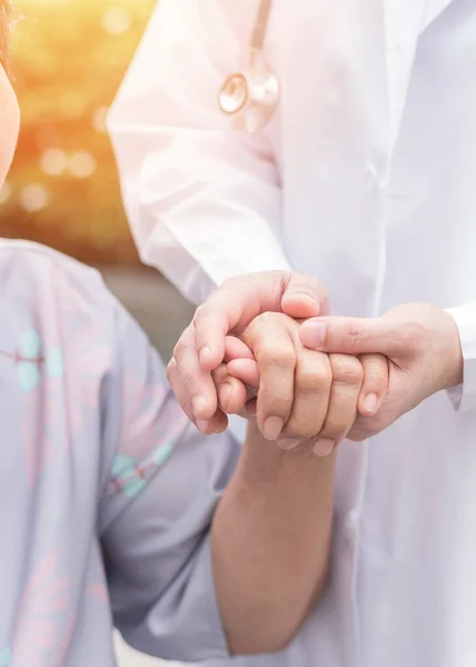 Huzurevinde yaşlı bunama hastası (yaşlanan yaşlı kişi) hastane bakıcısı ya da bakıcı sağlık hizmetlerinden mutlu sağlık hizmeti alan yaşlı bir doktorun elini tutuyor.