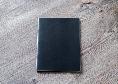 Dergi, kitapçık, broşür, menü, ahşap masa arkasındaki günlük tasarım şablonu için kitap modeli boş siyah A4 deri kapağı