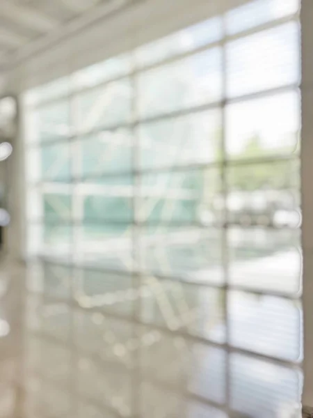 Office building lobby hall blur background or blurry school hallway corridor interior view looking toward empty corridor entrance, glass curtain wall and floor with exterior light illumination