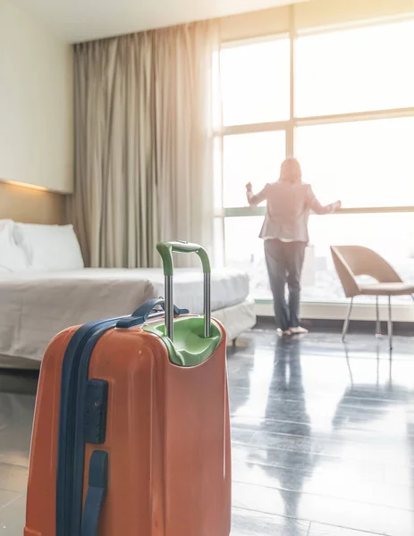 Luggage in hotel guest room with traveller lifestyle of  business woman staying for work travel or vacation trip looking out the window toward city view