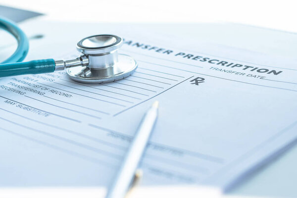 Doctor's notepad work with patient's medical health record blank paper form for prescription with stethoscope on table