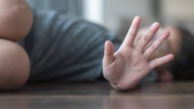 Çocuk istismarı ve suç önleme konsepti. Uluslararası Masum Çocuklar Günü Saldırganlık Mağdurları Günü 'nde elinde agresif eylemleri durduran bir çocukla yerde yatıyor.