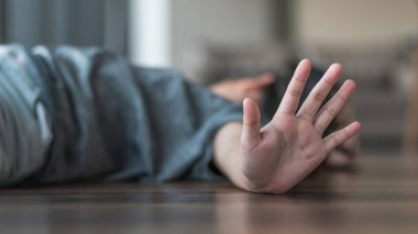 Çocuk istismarı ve suç önleme konsepti. Uluslararası Masum Çocuklar Günü Saldırganlık Mağdurları Günü 'nde elinde agresif eylemleri durduran bir çocukla yerde yatıyor.