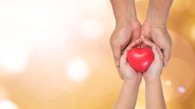 Babalar Günü kutlaması, seni seviyorum baba, baba ve çocuğun ellerinde ebeveynlik kavramı küçük çocuğun elini tutmak kırmızı kalbi desteklemek, yardım bağışı, evlatlık aile sağlık hizmetleri.