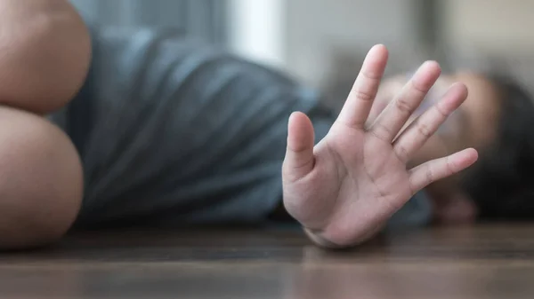 Çocuk istismarı ve suç önleme konsepti. Uluslararası Masum Çocuklar Günü Saldırganlık Mağdurları Günü 'nde elinde agresif eylemleri durduran bir çocukla yerde yatıyor.