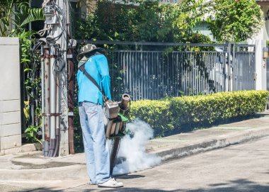 Sivrisinek buğulama spreyi ve böcek ilacı kontrolünün sıtmayı durdurması ve salgın hastalığını önlemesi için işçilerin kimyasal püskürtücü duman püskürtmesi.
