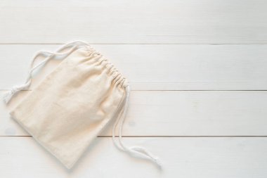 Asma ipli tuval, doğal pamuk kumaştan yapılmış küçük eko çuvalın maketi beyaz ahşap arka planda yatıyordu. 