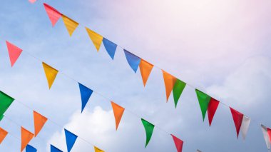 Eğlenceli bir şenlik için mavi gökyüzünde asılı açık renkli bir arka plan, yaz bayramı çiftliği ziyafeti, karnaval festivali etkinliği, park ya da sokak şenliği tasarımı için