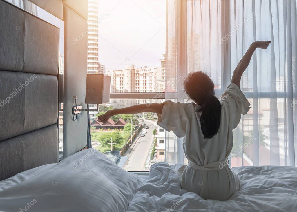 Hotel room comfort with good sleep easy relaxation lifestyle of Asian girl on bed have a nice day morning waking up, taking some rest, lazily relaxing in guest bedroom in city hotel 