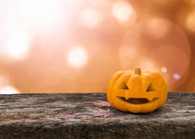 Cadılar Bayramı balkabağı Jack O 'Lantern yüzü ahşap masada portakal rengi arka planda