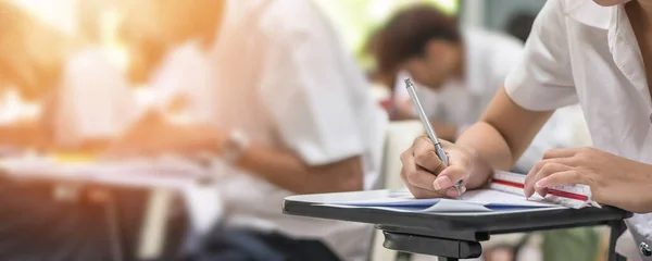 Exam at school with student\'s taking educational admission test in class, thinking hard, writing answer in university classroom, education and world literacy day concept