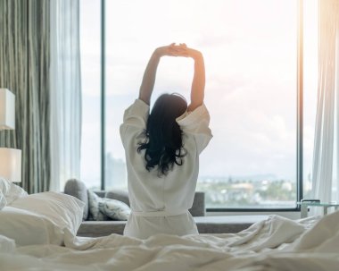 Kolay yaşam tarzı Asyalı bir kadın hafta sonu iyi bir uykudan uyanır biraz dinlenir, otel odasının penceresinde dinlenir iş hayatı kalitesi dengesi kavramının keyfini çıkararak mutlu bir gün geçirir.