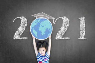 2021 yeni eğitim akademik takvimi yılı. Öğrenci çocuk, okul kutlaması için siyah karatahtayla dünya gezegenini büyütüyor. Sınıf çizelgesi.