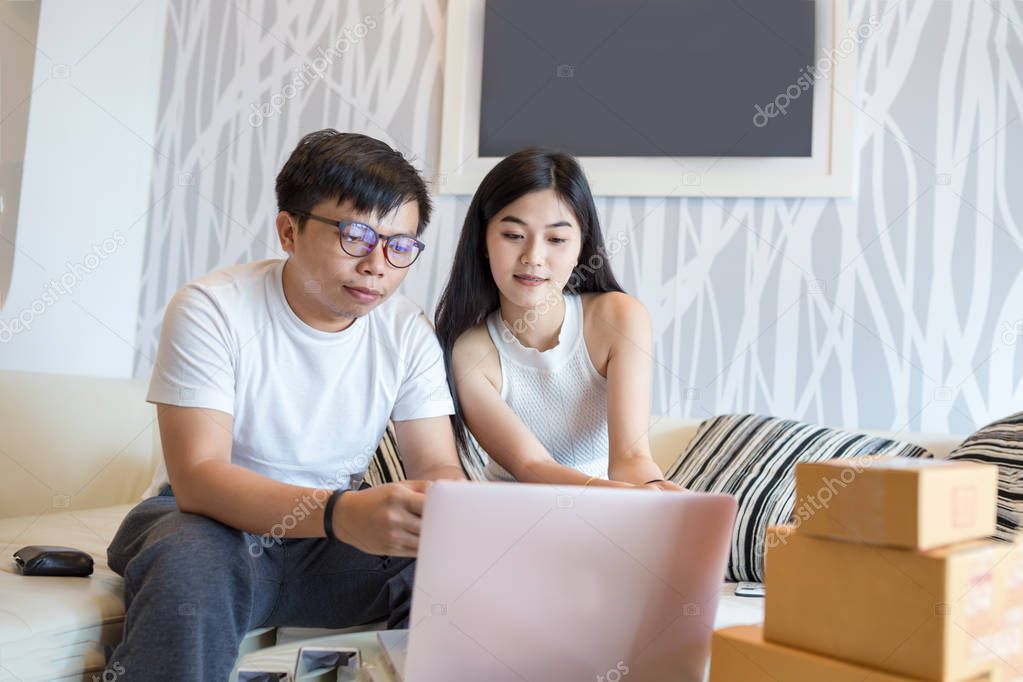 Young couple shopping online at laptop computer and pay with credit card and very happy in apartment of them. This is lifestyles of Asian young.