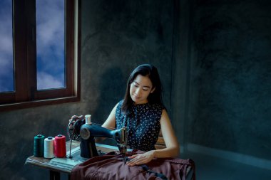 Asian girl enjoying and  sitting with sewing machine with ancient sewing machine.
