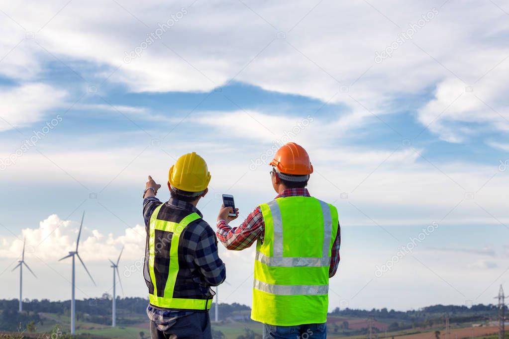 The engineers standing outdoor survey wind turbines green energy  together and analysis energy of wind turbine construction this is electric energy.