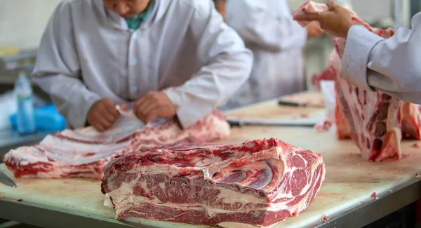 El carnicero cortando carne cruda en la carnicería — Foto de Stock