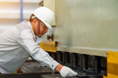 İşçiler fabrikada hidrolik basınç freniyle metal büküyorlar..