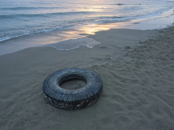 Забруднення океану пластиком: стара вантажівка шина (ціла) на пляжі — стокове фото