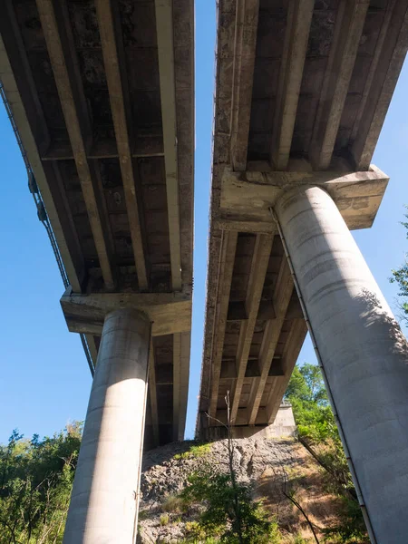 底から見える鉄筋コンクリートの柱を持つ複数のレーンハイウェイ橋 青い空の背景 — ストック写真